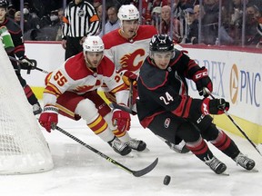 Carolina Hurricanes centre Seth Jarvis moves the puck against Calgary Flames defenceman Noah Hanifin and centre Adam Ruzicka at PNC Arena in 
in Raleigh, N.C., on Friday, Jan. 7, 2022.