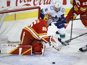 The Vancouver Canucks’ Matthew Highmore chases the puck as Calgary Flames goaltender Jacob Markstrom covers the net at Scotiabank Saddledome in Calgary on Saturday, Jan. 29, 2022.