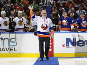 New York Islanders legend Clark Gillies waves to fans before conducting a ceremonial faceoff at Nassau Coliseum in Uniondale, N.Y., on Dec. 13, 2014.