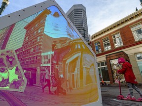 A little girl scoots by Oscillation, one of the Glow Festival art installations, as Stephen Avenue is reflected in the colourful crystal on Wednesday, February 9, 2022. Glow Fest is part of the Chinook Blast festivities, which run until Feb. 27.