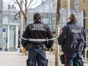 A transit peace officer and a member of the Calgary police are seen at City Hall station on Monday, February 28, 2022.