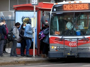 People wearing masks are seen boarding a city bus in downtown Calgary, Feb. 4, 2022.