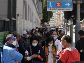 People wearing masks line up at a makeshift testing centre for COVID-19 following an outbreak in Hong Kong, China, Monday, Feb. 14, 2022.