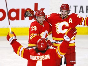 The Calgary Flames’ Johnny Gaudreau (left) celebrates with Sean Monahan and Rasmus Andersson after scoring a goal against the Florida Panthers at Scotiabank Saddledome in Calgary on Jan. 18, 2022.