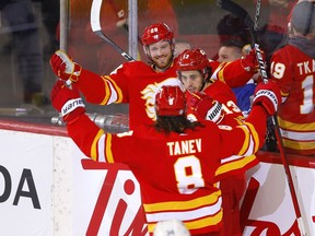 The Calgary Flames’ Elias Lindholm celebrates with goal against the Toronto Maples Leafs with Chris Tanev and Johnny Gaudreau at Scotiabank Saddledome in Calgary on Thursday, Feb. 10, 2022.
