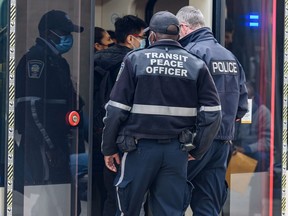 A transit peace officer and a member of the Calgary police board a CTrain at City Hall station on Monday, February 28, 2022.