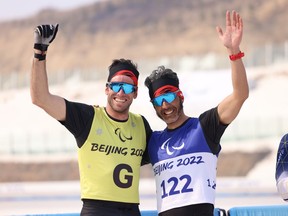 Brian McKeever (right) and his guide, Russell Kennedy, celebrates a gold-medal performance in the sprint free technique vision-impaired cross-country skiing event at the Zhangjiakou Medal Plaza during the Beijing 2022 Winter Paralympics on Wednesday, March 9, 2022.