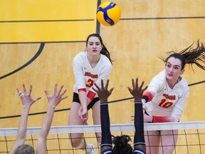 The University of Calgary Dinos Kenzie Vaandering, left, and Sophie Reed, right, both lunge toward the ball during a national quarter-final against the Trinity Western University Spartans at the Jack Simpson Gymnasium in Calgary on Friday, March 25, 2022.
