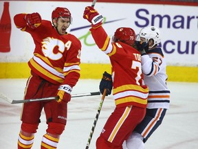 The Calgary Flames’ Mikael Backlund (left) celebrates a goal Tyler Toffoli as the Edmonton Oilers’ Brett Kulak looks on at Scotiabank Saddledome in Calgary on Saturday, March 26, 2022.