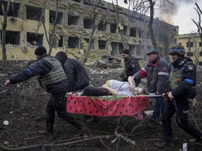 Ukrainian emergency employees and volunteers carry an injured pregnant woman from the damaged by shelling maternity hospital in Mariupol, Ukraine, Wednesday, March 9, 2022.