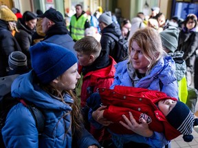 A woman holds a sleeping child as refugees wait for further transportation at the railway station in Przemysl, Poland on March 17, 2022.