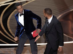 Chris Rock reacts after being hit by Will Smith (R) as Rock spoke on stage during the 94th Academy Awards in Hollywood, Los Angeles, California, U.S., March 27, 2022.