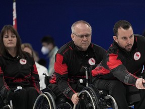 Canada's Jon Thurston pushes a stone as teammates Ina Forrest (left) and Dennis Thiessen (centre) look on during their wheelchair curling competition against Norway at the 2022 Winter Paralympics, Thursday in Beijing.