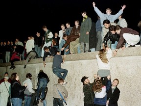 East and West German citizens celebrate as they climb the Berlin wall at the Brandenburg gate after the opening of the East German border was announced in Berlin, Germany, November 9, 1989.