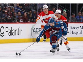 Colorado Avalanche centre Darren Helm controls the puck ahead of Calgary Flames forwards Brett Ritchie (24) and Sean Monahan at Ball Arena in Denver on Sunday, March 13, 2022.