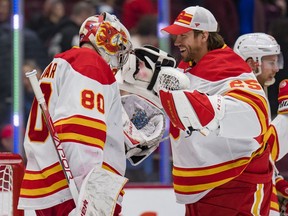Calgary Flames goaltenders Dan Vladar and Jacob Markstrom celebrate the club’s 5-2 win over the Vancouver Canucks at Rogers Arena in Vancouver on Saturday, March 19, 2022.