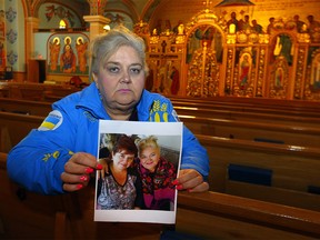 Ukrainian/Canadian Christine Moussienko holds a photo of her and her sister-in-law Svetlana Moussienko as she prays at the Ukrainian church in Calgary on Wednesday, March 2, 2022.