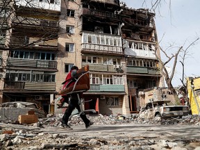 FILE PHOTO: A local resident carries an armchair outside a block of flats heavily damaged during the Ukraine-Russia conflict in the southern port city of Mariupol, Ukraine on April 25, 2022.