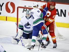 Calgary Flames winger Milan Lucic battles Vancouver Canucks winger Juho Lammikko as goalie Thatcher Demko looks on at the Scotiabank Saddledome in Calgary on Saturday, April 23, 2022.