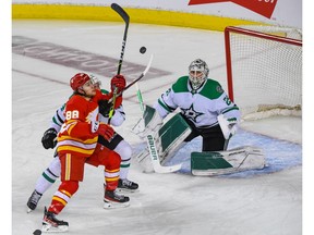 Calgary Flames forward Andrew Mangiapane battles with Dallas Stars forward Joel Hanley in front of Stars goaltender Jake Oettinger during Game 7 of their first-round playoff series at Scotiabank Saddledome on Sunday, May 15, 2022.