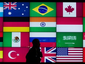 A man walks past a screen displaying flags of G20 countries inside of the COEX convention centre in Seoul, South Korea.