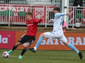 Cavalry FC’s Myer Bevanmakes a cross in front of FC Edmonton defender Cale Loughrey during their Canadian Championship first-round match on ATCO Field at Spruce Meadows on Tuesday, May 10, 2022.