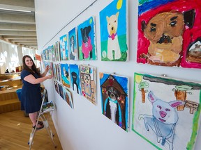 Foundations for the Future Charter Academy teacher Rebecca Carruthers-Green hangs some of her Grade 4 students’ art from the Empathy Pawject at the Central Library on Thursday, May 26, 2022. The project had students paint portraits of dogs that were up for adoption at local animal rescue societies to help find homes for the dogs.