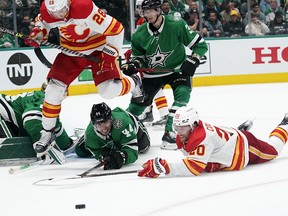Calgary Flames centre Elias Lindholm (28), Dallas Stars defenseman Joel Hanley (44) and Flames centre Blake Coleman (20) compete for the puck during the second period of Game 3 of an NHL hockey Stanley Cup first-round playoff series Saturday, May 7, 2022, in Dallas.