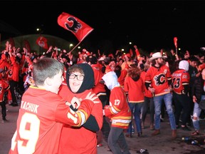 Calgary Flames fans react to the action on a large outdoor screen at the Red Lot viewing party outside the Saddledome during Game 5 of the Stanley Cup playoffs against the Dallas Stars. Wednesday, May 11, 2022.