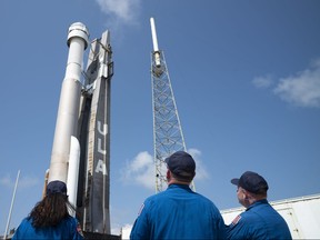 In this handout photo provided by NASA, NASA astronauts (left to right) Suni Williams, Barry "Butch" Wilmore, and Mike Fincke watch as a United Launch Alliance Atlas V rocket with Boeings CST-100 Starliner spacecraft aboard is rolled out of the Vertical Integration Facility to the launch pad at Space Launch Complex 41 ahead of the Orbital Flight Test-2 (OFT-2) mission on May 18, 2022 in Cape Canaveral, Fla.