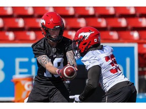 Quarterback Bo Levi Mitchell hands off to running back Ka'Deem Carey during Calgary Stampeders training camp at McMahon Stadium on Monday, May 16, 2022.