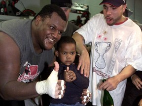 Four-year-old T.J. Rayam sits in the Grey Cup as his father, Calgary Stampeders offensive lineman Thomas Rayam (left) and teammate Ben Sankey look on after the Stamps defeated the Winnipeg Blue Bombers 27-19 to win the CFL title at Olympic Stadium in Montreal on Nov. 25, 2001.