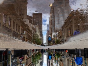 Buildings along Stephen Avenue in downtown Calgary are reflected in rainwater on Friday, June 24, 2022.
