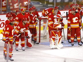 The Flames gather around goaltender Jacob Markstrom after losing in overtime to the Edmonton Oilers in Game 5 on May 26.