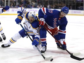 Zemgus Girgensons #28 of the Buffalo Sabres and Kevin Rooney #17 of the New York Rangers fight for the face off in the first period at Madison Square Garden on November 21, 2021 in New York City.