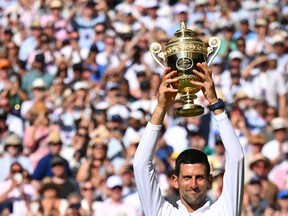 Serbia's Novak Djokovic raises his trophy after defeating Australia's Nick Kyrgios during the men's singles final tennis match on the fourteenth day of the 2022 Wimbledon Championships at The All England Tennis Club in Wimbledon, southwest London, on July 10, 2022