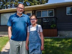 Cory Banks and his daughter Molly, 10, pose for a photo outside their house in Calgary on Friday. Molly’s custom-made bike was stolen while the family was moving from Airdrie to Calgary.