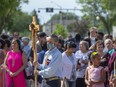 Elmer Waniandy holds a cross that will lead the procession into the church. Sacred Heart Church of the First Peoples was damaged by fire in the spring of 2020 and the reconstruction has been pushed along by a visit by Pope Francis in July 2022. The church was dedicated on July 17, 2022.