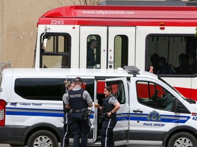 Calgary Transit peace officers gather near a Calgary Transit van as a CTrain passes in the background on Tuesday, June 7, 2022.