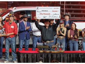 Kris Molle from Chauvin, Alberta, raises his cheque for winning the Cowboys Rangeland Derby championship at the Calgary Stampede chuckwagon races in Calgary, Ab., on Sunday, July 17, 2022. Mike Drew/Postmedia