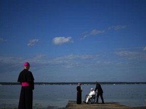 Pope Francis gets water from the lake after blessing it during the annual pilgrimage event in Lac Ste. Anne, Alta., Tuesday, July 26, 2022.