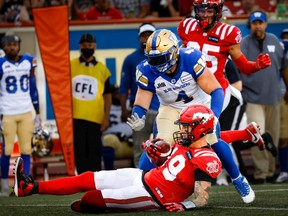 Calgary Stampeders quarterback Bo Levi Mitchell slides for a first down in front of Winnipeg Blue Bombers linebacker Adam Bighill at McMahon Stadium in Calgary on Saturday, July 30, 2022.