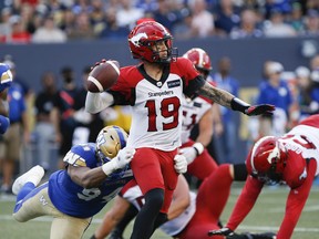 Winnipeg Blue Bombers' Jackson Jeffcoat (94) gets a hold of Calgary Stampeders quarterback Bo Levi Mitchell (19) as he throws during the first half of CFL action in Winnipeg, Friday, July 15, 2022.