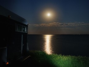 Moonlight tinted yellow by a bit of smoke in the air glints off McGregor Lake by Milo, Ab., on Monday, August 8, 2022.