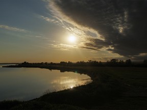 Yellow moonlight tints incoming clouds at McGregor Lake by Milo, Ab., on Monday, August 8, 2022.