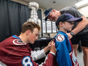 Colorado Avalanche player and Calgarian Cale Makar signs four-year-old Parker's jersey as his father Paul Hughes watches at Crowchild Twin arena in Calgary on Thursday, August 11, 2022.