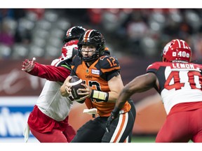 VANCOUVER, BRITISH COLUMBIA - OCTOBER 16: Quarterback Nathan Rourke #12 of the BC Lions scrambles while being pressured by Shawn Lemon #40 of the Calgary Stampeders during the second half of CFL football action at BC Place on October 16, 2021 in Vancouver, British Columbia, Canada.