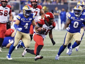 Stampeders running back Peyton Logan is pursued by Blue Bombers linebackers Adam Bighill (left) and Malik Clements during Thursday's game.
