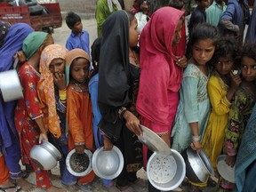 People from flood-affected areas wait to receive food distributed by the Saylani Welfare Trust, in Lal Bagh, Sindh province, Pakistan, Tuesday, Sept. 13, 2022.