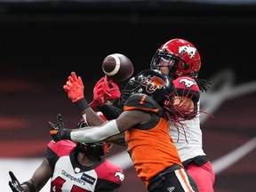 B.C. Lions' Lucky Whitehead, front, fails to make the reception as Calgary Stampeders' Javien Elliott, back right, and Trumaine Washington defend during the first half of CFL football game in Vancouver, on Saturday, September 24, 2022.
